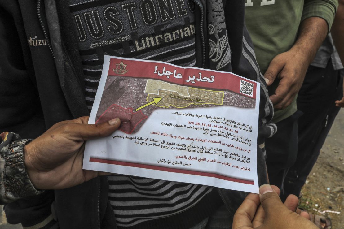 Palestinians hold an evacuation order leaflet dropped by Israel's military in the east of the city of Rafah on May 6, 2024