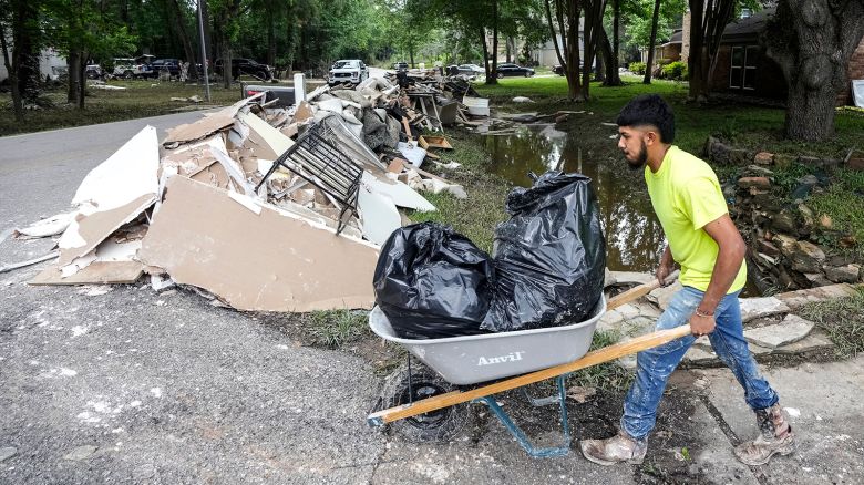 A construction worker moves trash bags full of flood-damaged items to a debris pile while cleaning up from flood damage in the River Plantation neighbourhood on Monday, May 6, 2024 in Conroe, Texas.