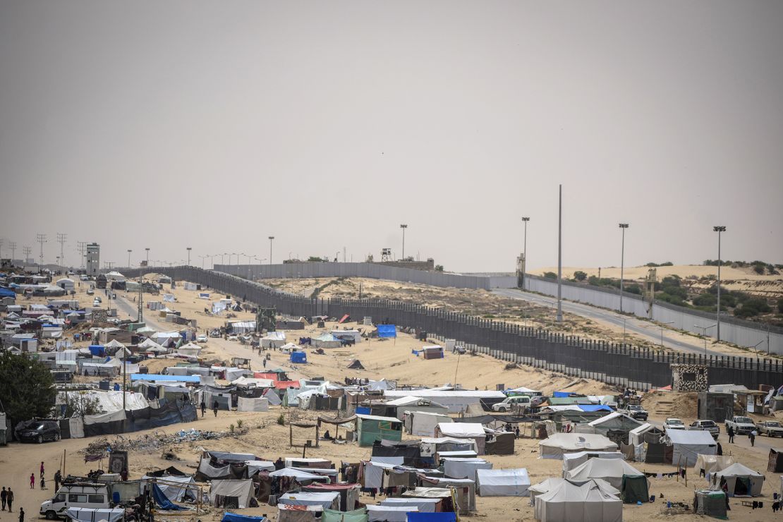 Palestinians displaced by the Israeli air and ground offensive on the Gaza Strip walk through a makeshift tent camp in Rafah on the border with Egypt, in Gaza on May 10.