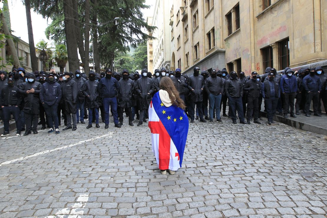 A protester, draped with Georgian national and European Union flags, stands before police officers blocking the way to the country's parliament building on Tuesday.