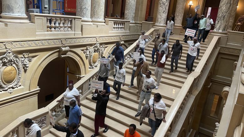 Dozens of protesters descend a staircase in the Minnesota State Capitol building in St. Paul, Minn., Friday, May 17, 2024, while holding signs and pushing for a law that would require ride-hailing companies – including Uber and Lyft -- to increase pay for drivers in the state. Uber and Lyft have said they will leave the state if Minnesota lawmakers pass legislation requiring the companies to raise driver pay by more than the companies want to.