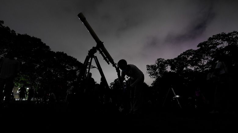 In this 2022 file photo, a girl looks at the moon through a telescope in Caracas, Venezuela. Six planets will line up in the early morning sky on June 3, 2024, but most won't be visible to the naked eye. A planetary parade happens relatively often when several planets align on the right side of the sun, making them visible across a narrow band of our sky.