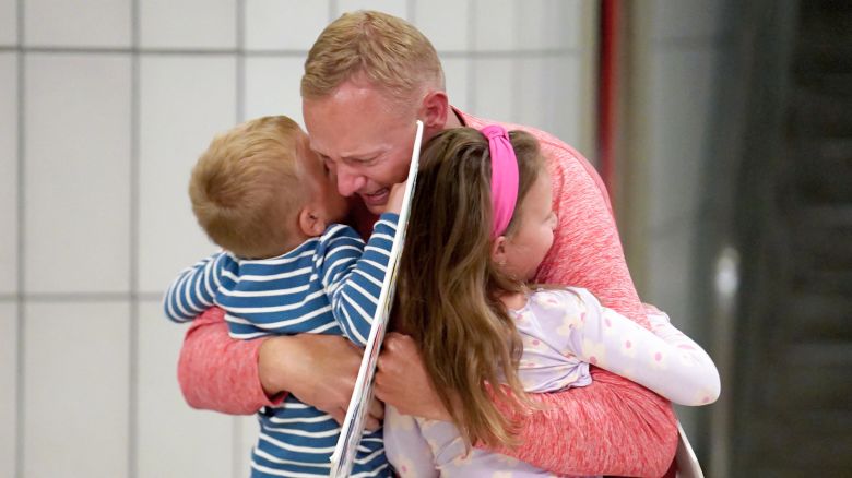 Bryan Hagerich hugs his children, Palmer, 4, left, and Caroline, 6, right, after arriving at Pittsburgh International Airport Friday, May 24, 2024, in Pittsburgh. Hagerich was arrested in the Caribbean for illegally carrying ammunition and returned to the United States after receiving a suspended sentence of one year and a fine of several thousand dollars.