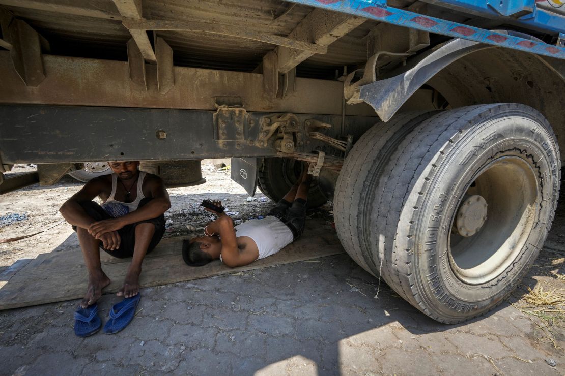 Workers take refuge beneath a parked truck from the scorching heat in Guwahati, India, Saturday, May 25, 2024.