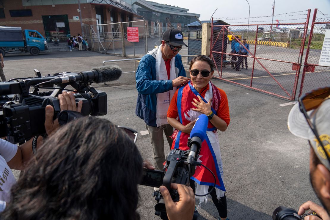 Kim Lal Gautam places the Nepali flag on Phunjo Lama on her arrival at the airport in Kathmandu.