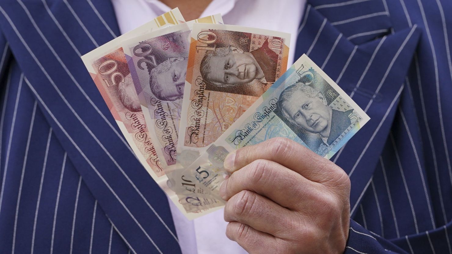 A person holds some of the newly released banknotes, featuring the portrait of King Charles III, outside the Bank of England, London, Wednesday, June 5, 2024.