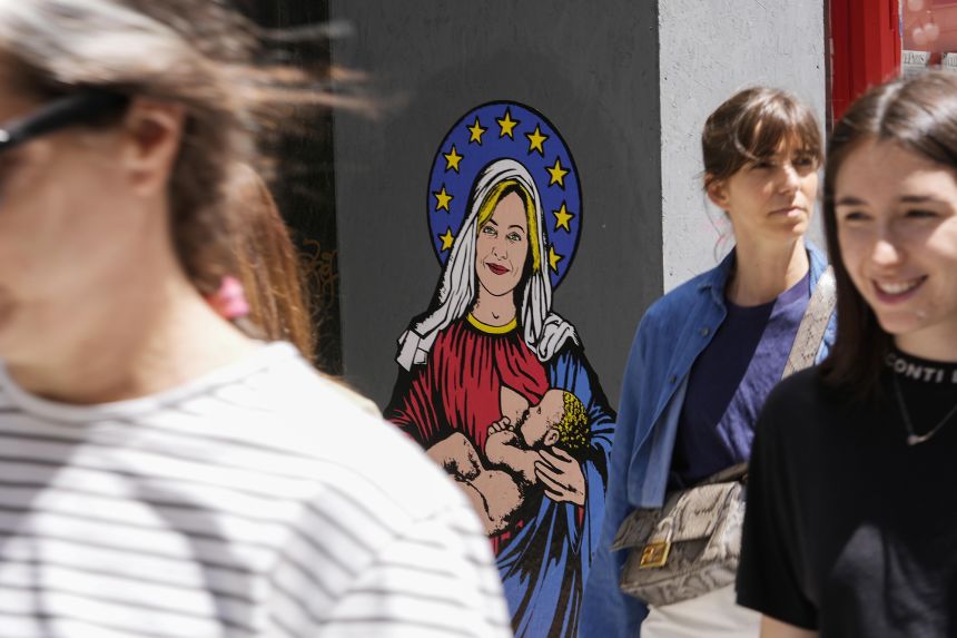 People pass a mural titled 