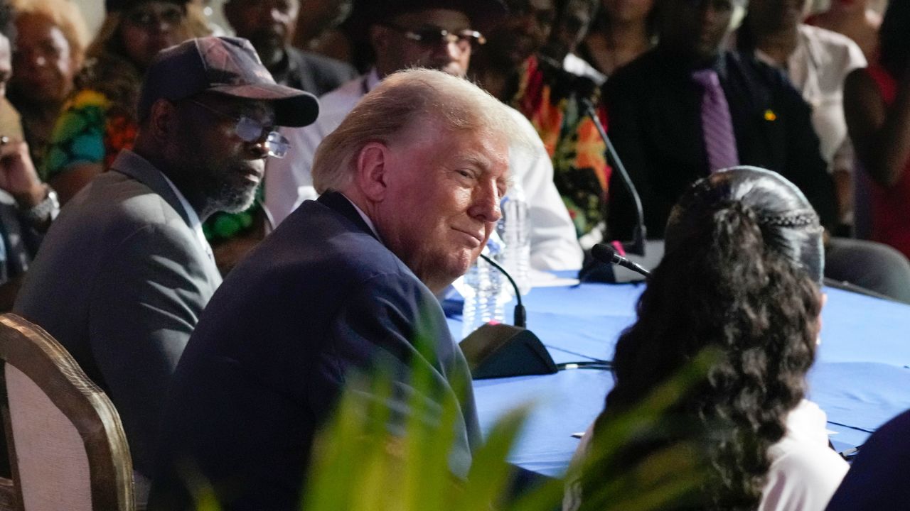 Republican presidential candidate former President Donald Trump looks to Itasha Dotson, right, as Carlos Chambers listens at a campaign event at 180 Church, Saturday, June 15, 2024, in Detroit. (AP Photo/Carlos Osorio)