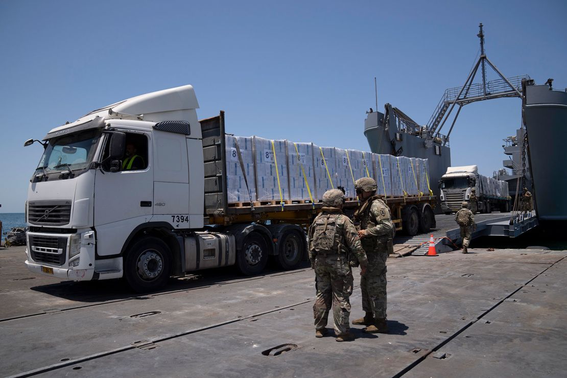 US Army soldiers stand next to trucks arriving loaded with humanitarian aid at the US-built floating pier Trident before reaching the beach on the coast of the Gaza Strip on June 25, 2024.
