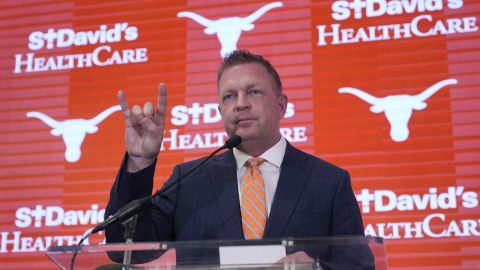 Jim Schlossnagle flashes a hook'em sign as he speaks at a news conference after he was introduced as the new NCAA college head baseball coach at Texas, Wednesday, June 26, 2024, in Austin, Texas. Schlossnagle left rival program Texas A&M. (AP Photo/Eric Gay)