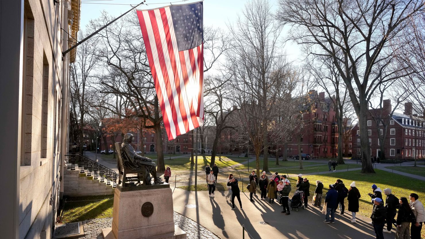People take photos near a John Harvard statue on the Harvard University campus in Cambridge, Massachusetts, on January 2, 2024.