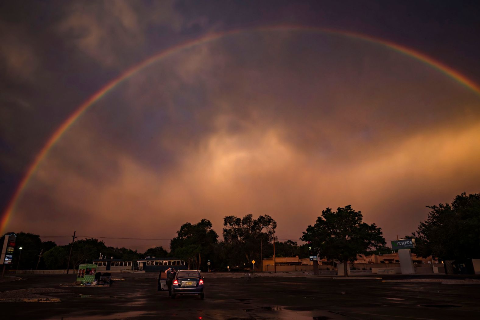 A woman photographs a rainbow in a parking lot in Albuquerque, New Mexico, on Tuesday, July 2.