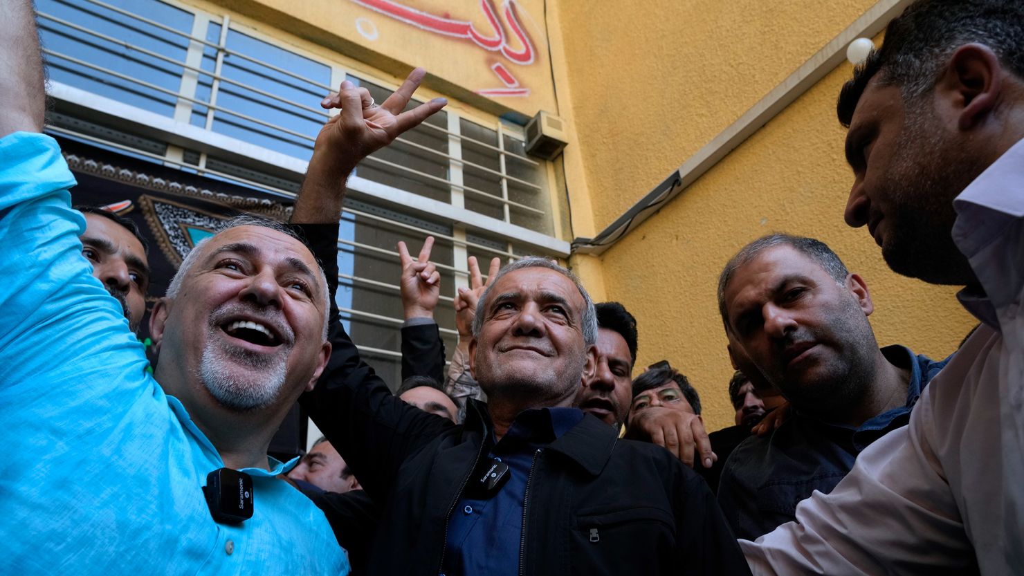 Masoud Pezeshkian, center, flashes a victory sign after casting his vote as he is accompanied by former Foreign Minister Mohammad Javad Zarif, left, at a polling station in Shahr-e-Qods near Tehran, Iran, on Friday.