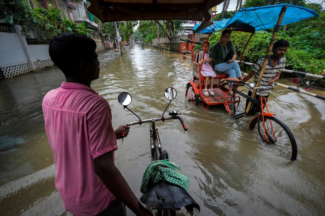 Rickshaw pullers transport passengers through a flooded road after heavy monsoon rain in Guwahati, India, Friday, July 5, 2024.