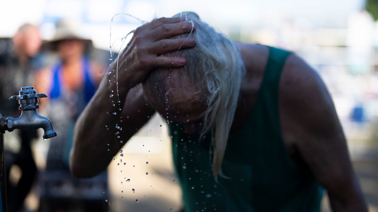 A person cools off during the Waterfront Blues Festival on Friday, July 5, 2024, in Portland, Ore. A slow-moving and potentially record-setting heat wave is spreading across the Western U.S., sending many residents in search of a cool haven from the dangerously high temperatures. (AP Photo/Jenny Kane)