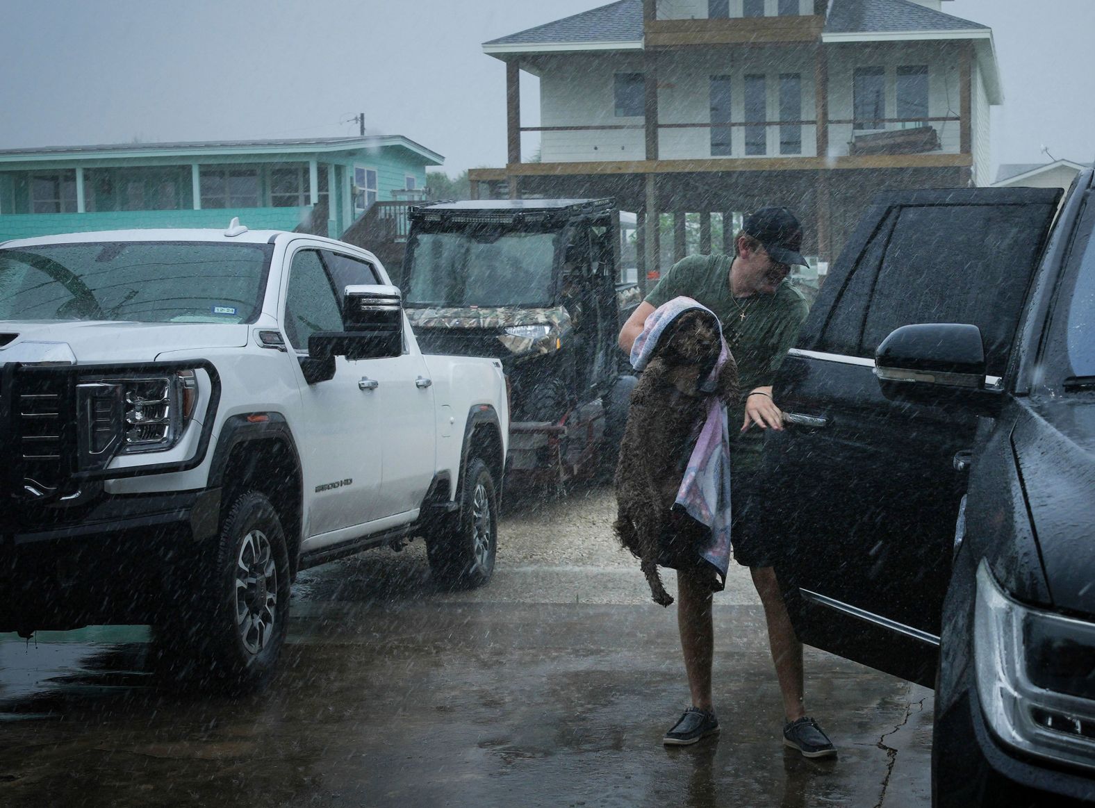 Blake Braun loads his dog Dolly into his family's vehicle as Beryl's outer bands from Beryl begin to hit Port O'Connor, Texas, on Sunday.