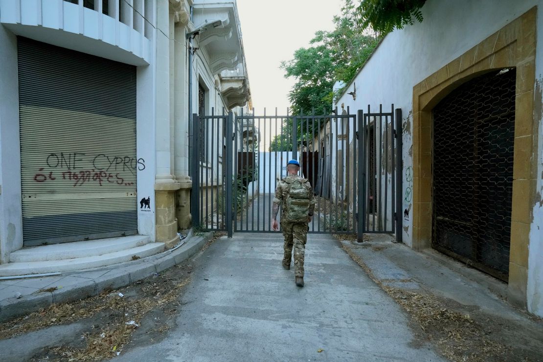 A UN Peacekeeper walks towards to a gate by the abandoned buildings inside the UN-controlled buffer zone in the central of Nicosia on June 18.