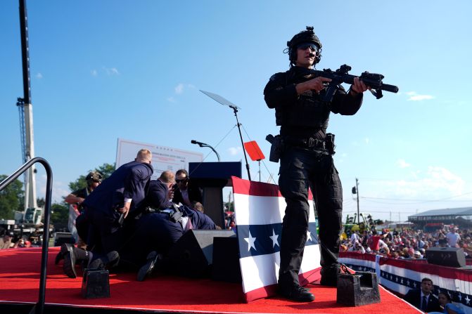 Trump is covered by Secret Service agents after loud bangs were heard at the rally.