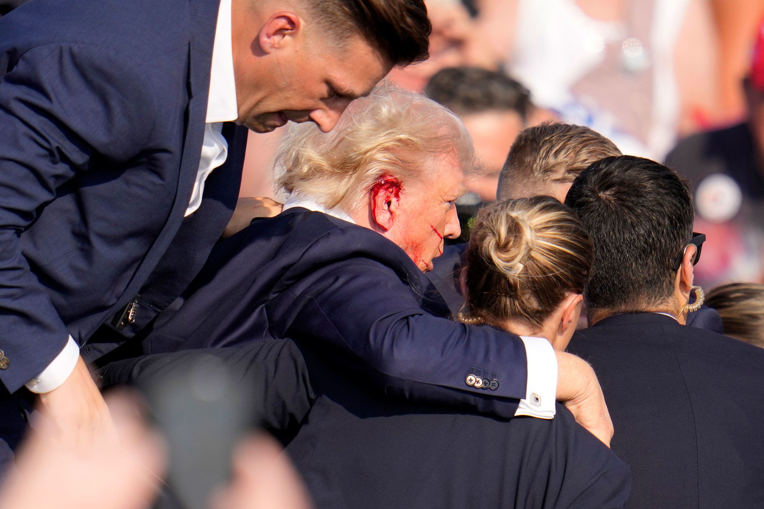 Se ve sangre en la oreja derecha de Trump mientras lo ayudan a salir del escenario.