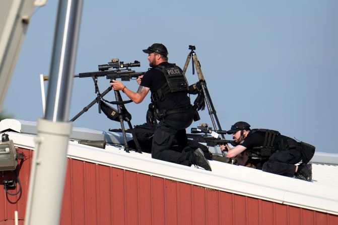 Police snipers are seen above the rally. A law enforcement source and a police officer at the scene told CNN <a href="https://www.cnn.com/politics/live-news/election-biden-trump-07-13-24#h_2213990564fb532dab0780858b3ec1be">the shooter was positioned on a building rooftop just outside the rally venue</a>.