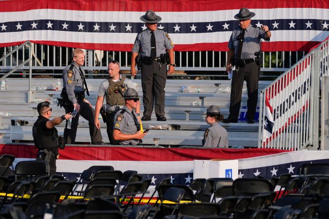 Law enforcement officers work at the empty rally site after the shooting.