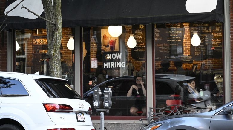 A "Now Hiring" sign advertising job openings is viewed in the window of a cafe, Monday, July 8, 2024, in Boston.