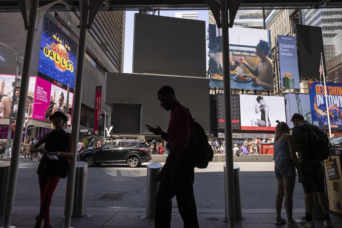 Pedestrians walk by blacked out screens due to a global technology outage in Times Square, Friday, July 19, 2024, in New York.