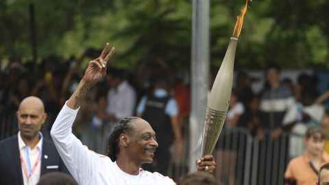 Snoop Dogg carries the Olympic torch at the 2024 Summer Olympics, Friday, July 26, 2024, in Saint-Denis, outside Paris, France. (AP Photo/Aurelien Morissard)