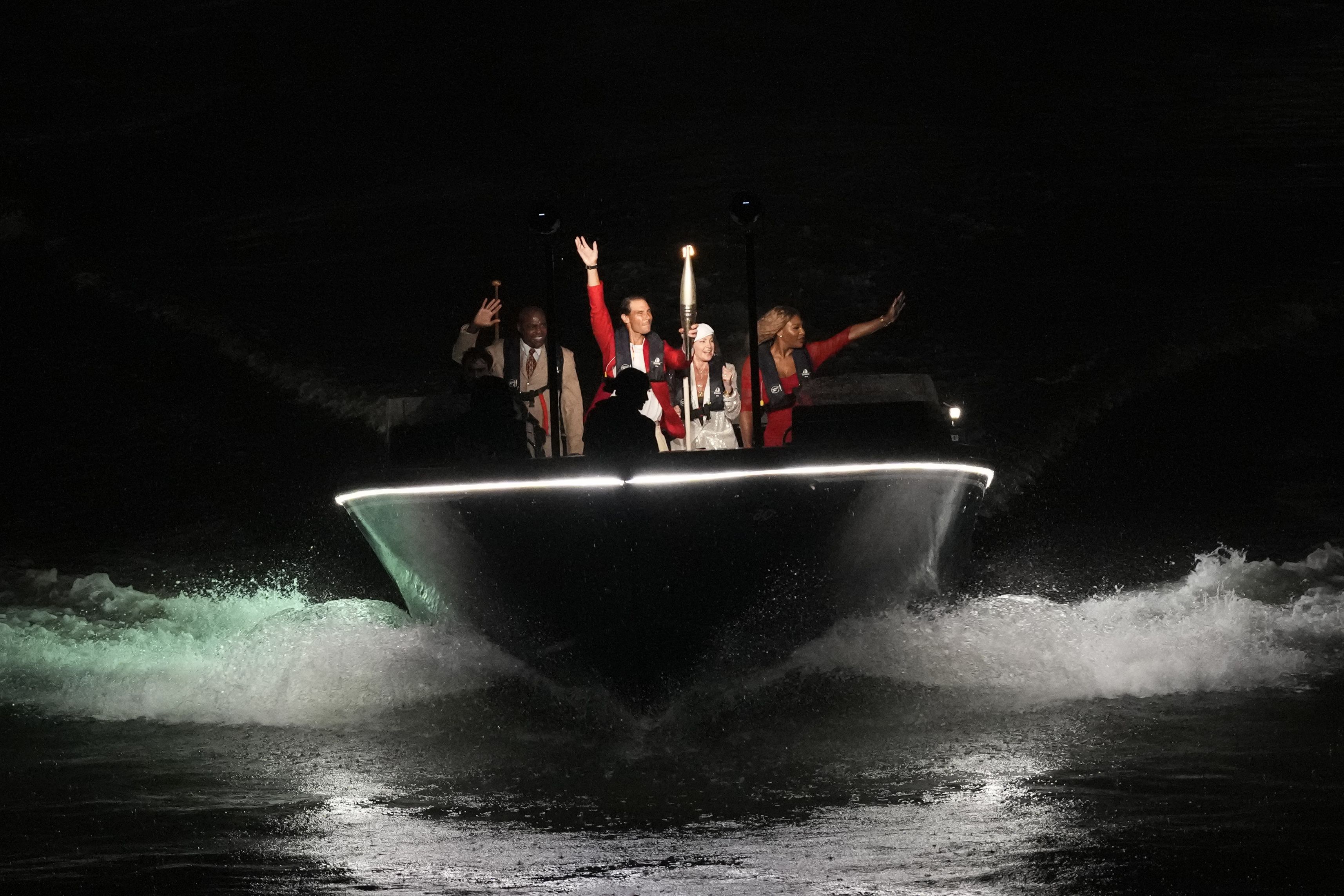 Tennis star Rafael Nadal carries the Olympic flame aboard a boat with a few famous former Olympians: from left, Carl Lewis, Nadia Comăneci and Serena Williams.