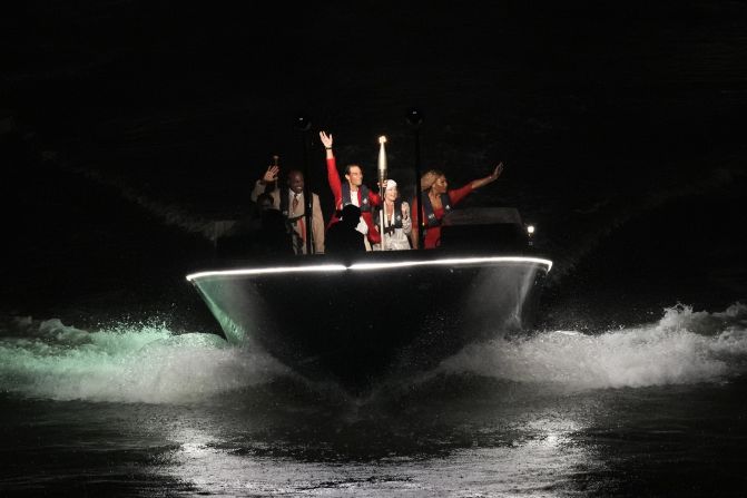 Tennis star Rafael Nadal carries the Olympic flame aboard a boat with a few famous former Olympians: from left, Carl Lewis, Nadia Com?neci and Serena Williams.