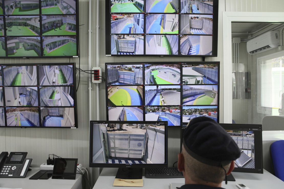 An Italian police officer sits in front of screens showing images from surveillance cameras in the Italian refugee arrival camp in the port city of Shengjin in northern Albania, on August 1, 2024.