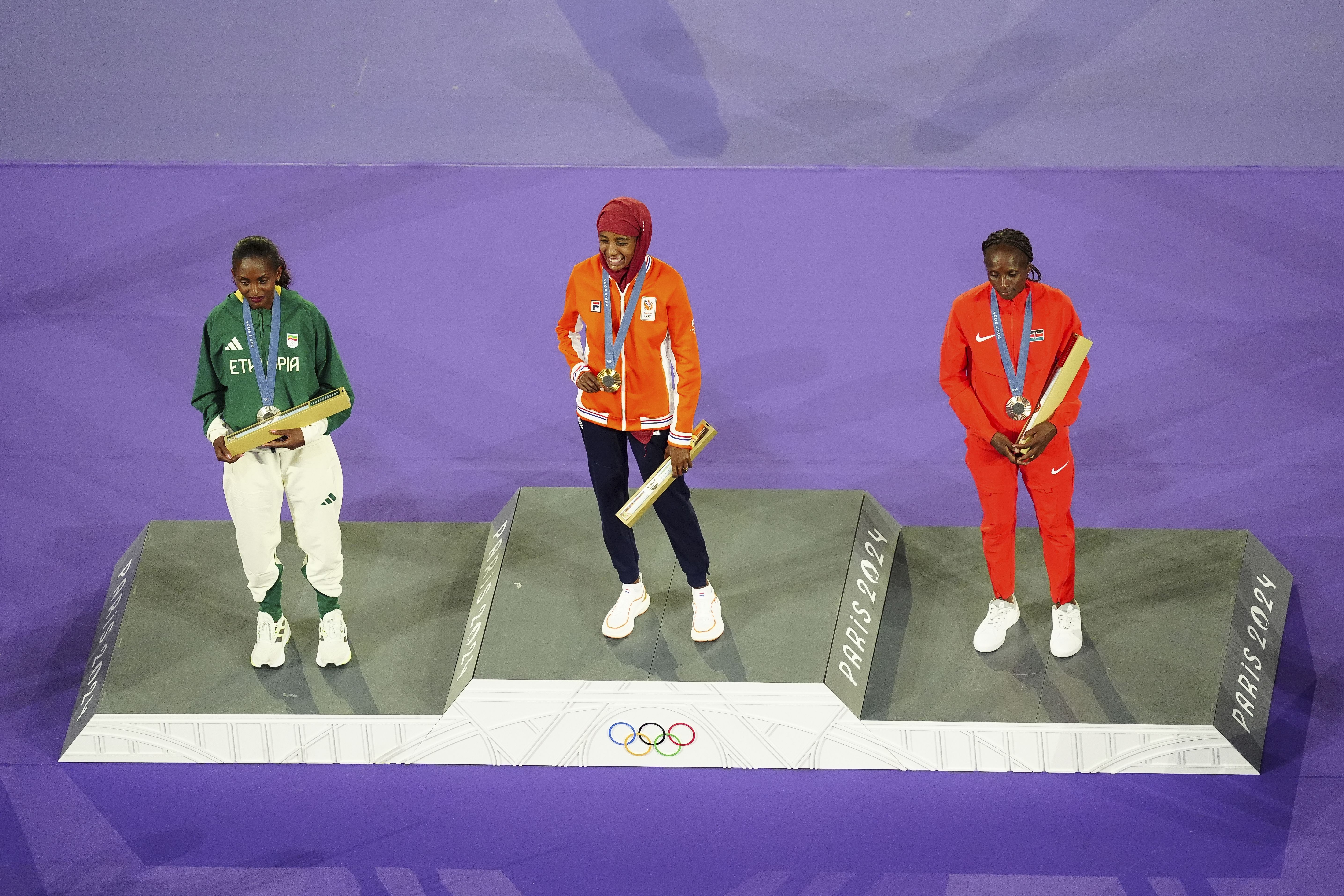 From left, Ethiopia's Tigst Assefa, the Netherlands' Sifan Hassan and Kenya's Hellen Obiri stand for a medal ceremony held during the closing ceremony.