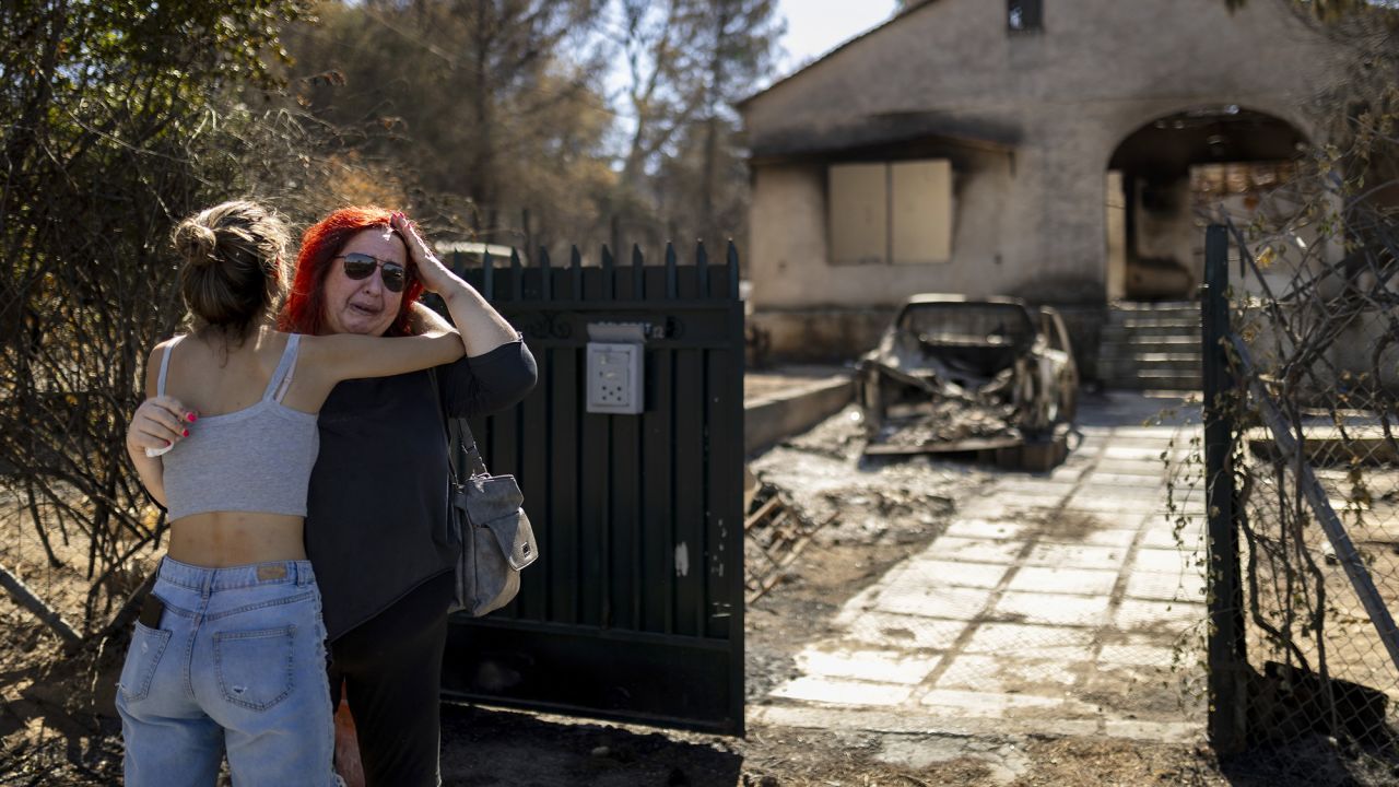 13 August 2024, Greece, Athen: A woman is comforted by a girl in front of her burnt-down house, which was destroyed by a forest fire in Ano Patima near Penteli in the north of Athens. Just a few kilometers northeast of the Greek capital, firefighters are battling countless fires over an area of around 200 square kilometers. The government has now asked the EU for support. Photo by: Socrates Baltagiannis/picture-alliance/dpa/AP Images