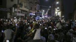 People gather in the streets as Olympic gold medalist Imane Khelif waves from the top of a double decker bus.