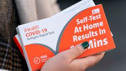 FILE - A woman holds two boxes of at-home Covid-19 test kits in Washington, Dec. 22, 2021. (AP Photo/Andrew Harnik, File)