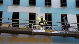 A worker paints the side of a building on Monday, Aug. 26, 2024, in Portland, Ore.