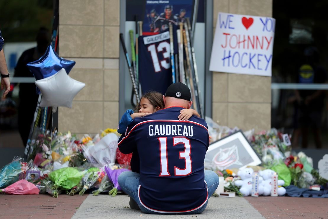 Shiloh Rivera, facing, mourns with Hylas Stemen of Columbus, at the makeshift memorial set up by fans for Blue Jackets hockey player Johnny Gaudreau in Columbus, Ohio, Friday, Aug. 30, 2024.