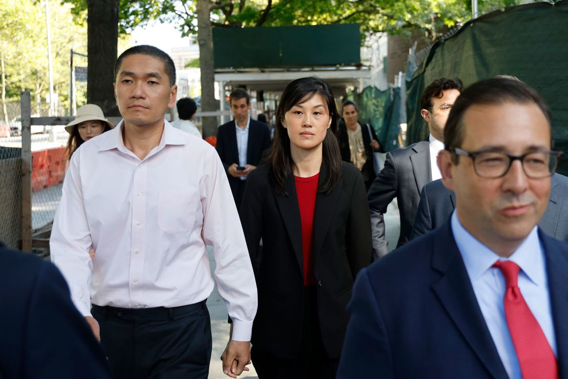 Attorney Seth DuCharme walks in front of Linda Sun, center, and her husband, Christopher Hu, left, as they leave Brooklyn Federal Court after their arraignment, Tuesday.