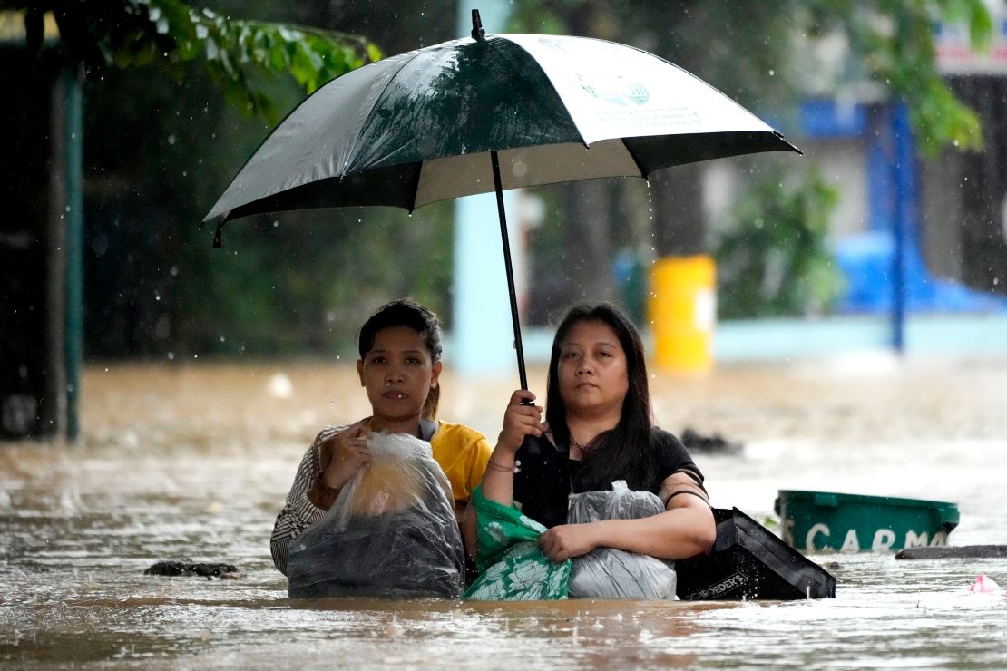 Residents protect their belongings as they negotiate a flooded street caused by heavy rains from Tropical Storm Yagi, locally called Enteng, in Cainta, Rizal province, Philippines, on September 2, 2024.