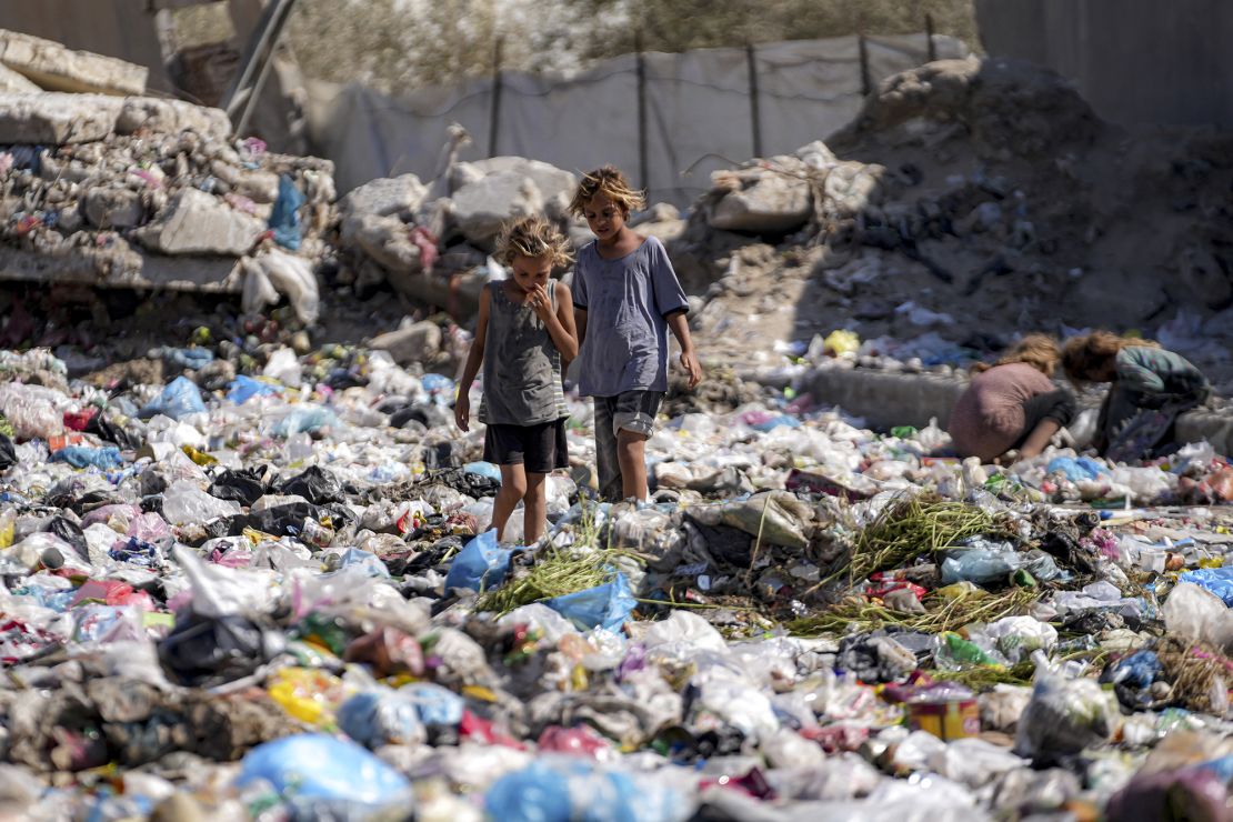 Displaced children sort through trash at a street in Deir Al-Balah, central Gaza Strip, on August 29.