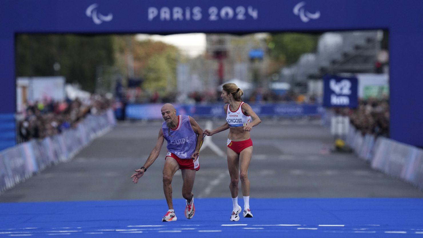 Mia Carol stumbles as he and Elena Congost approach the finish line in the women's T12 marathon.