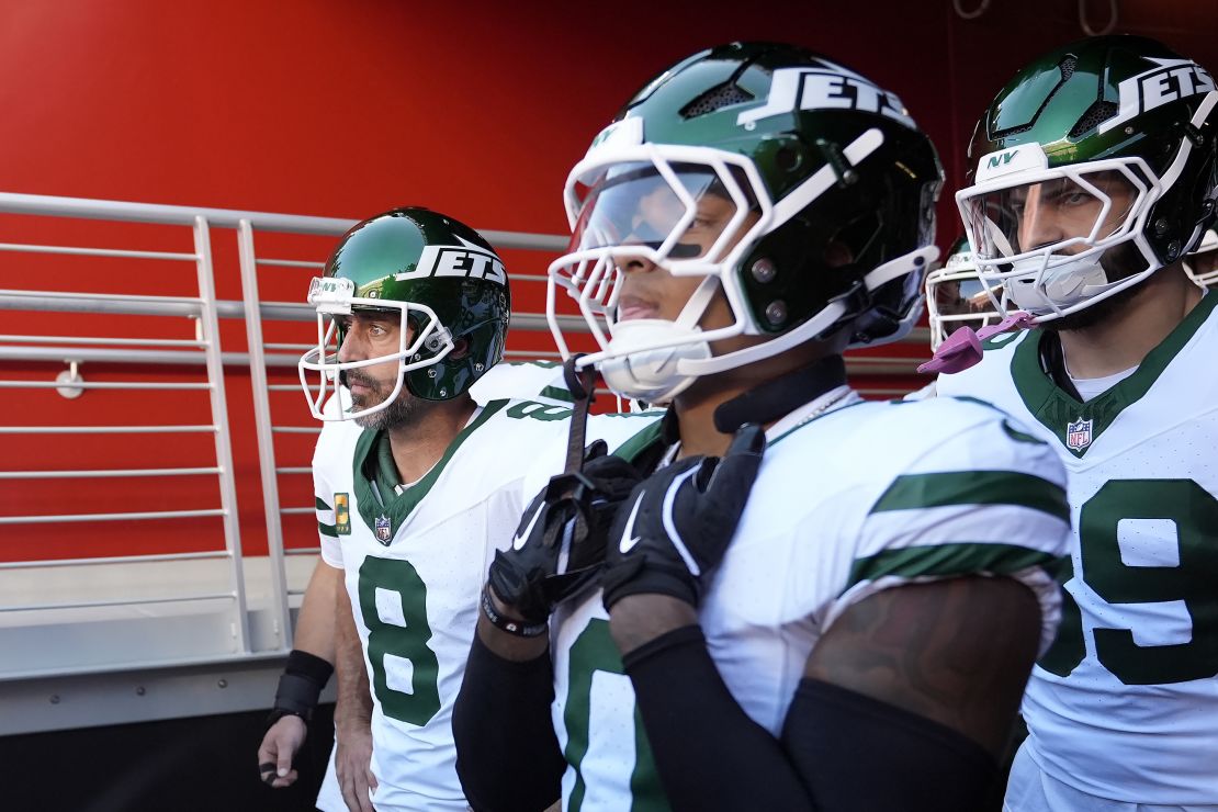 Jets QB Aaron Rodgers (left) and teammates prepare to take the field.