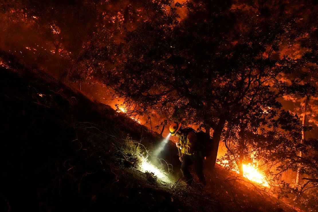 A firefighter walks up a hill as the Bridge Fire burns near homes in Wrightwood, California, on Tuesday.