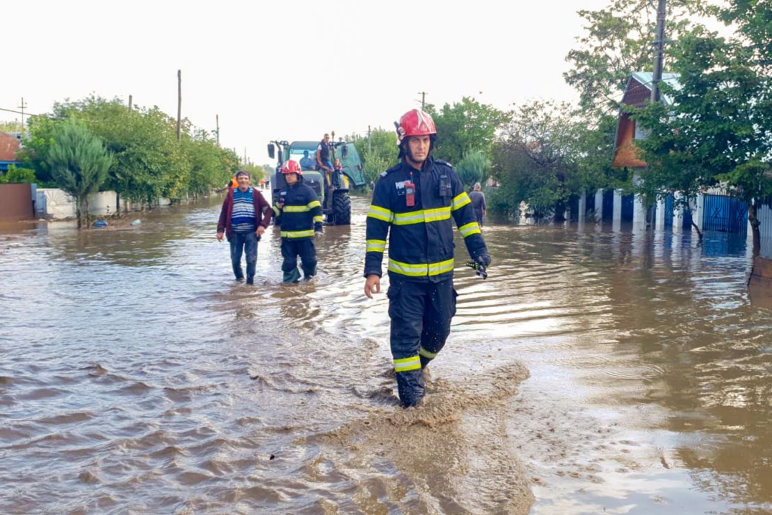 Rescuers assist the locals on a flooded street in Pechea, Romania, on Saturday.