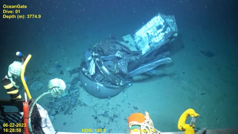 A video still frame shows the remains of the Titan submersible, center, on the floor of the Atlantic Ocean.