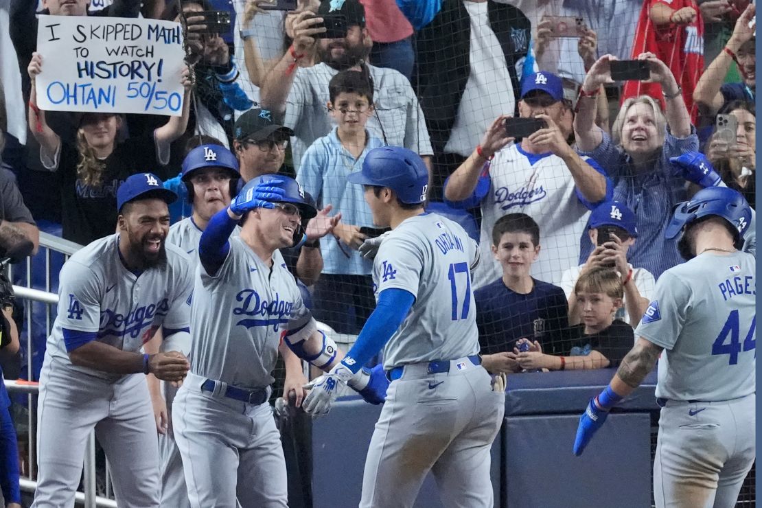 Shohei Ohtani (17) of the Los Angeles Dodgers is congratulated by teammates after hitting a home run to score Andy Pages in the seventh inning of a baseball game against the Miami Marlins, Thursday, Sept. 19, 2024, in Miami. (AP Photo/Wilfredo Lee)