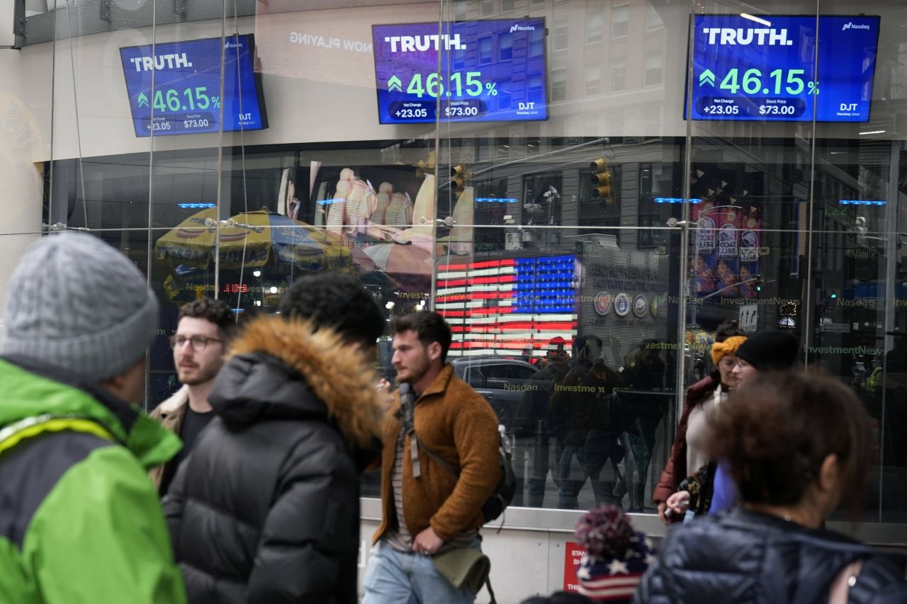 Pedestrians walk past the Nasdaq building as the stock price of Trump Media & Technology Group Corp. is displayed on screens in March 2024 in New York.