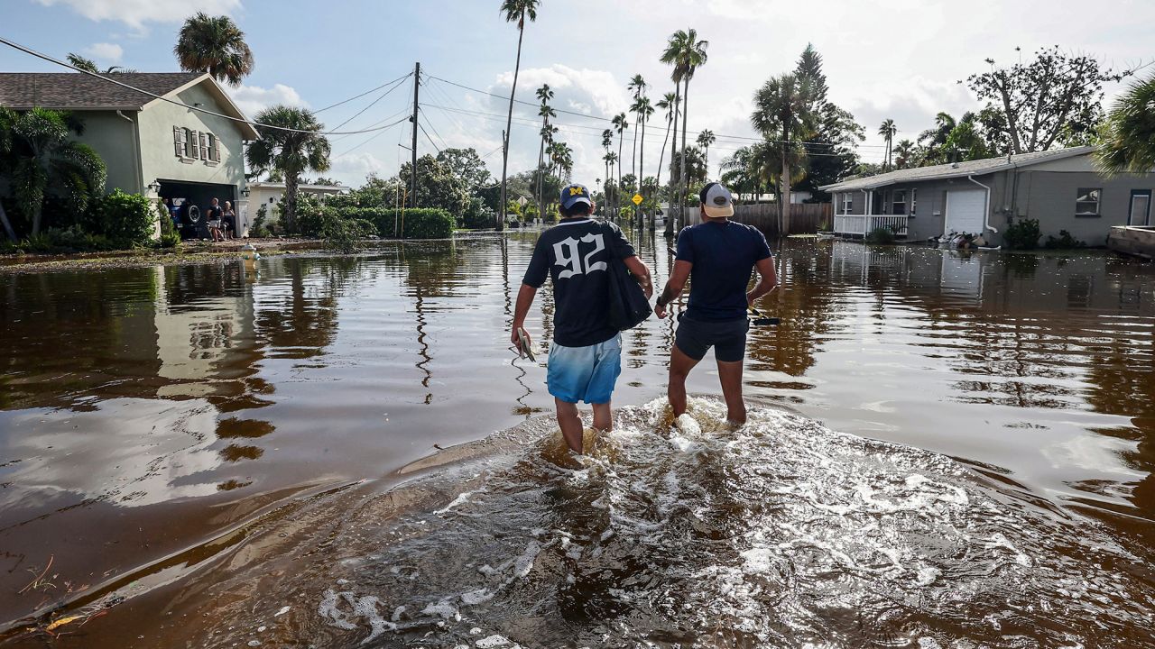 Thomas Chaves, left, and Vinny Almeida walk through floodwaters from Hurricane Helene in St. Petersburg, Florida, on Friday.