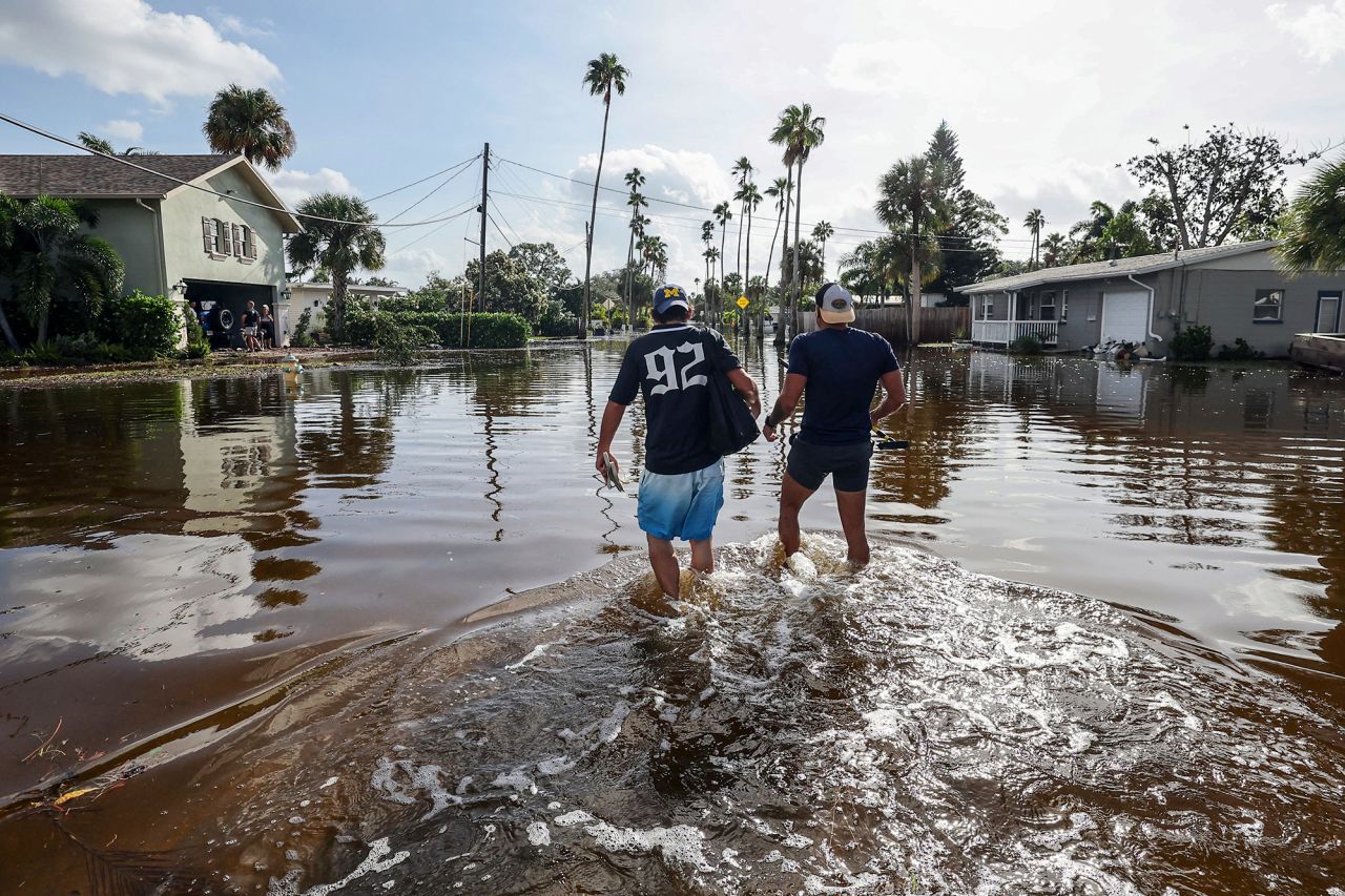 Thomas Chaves, left, and Vinny Almeida walk through floodwaters from Hurricane Helene in St. Petersburg, Florida, on Friday.