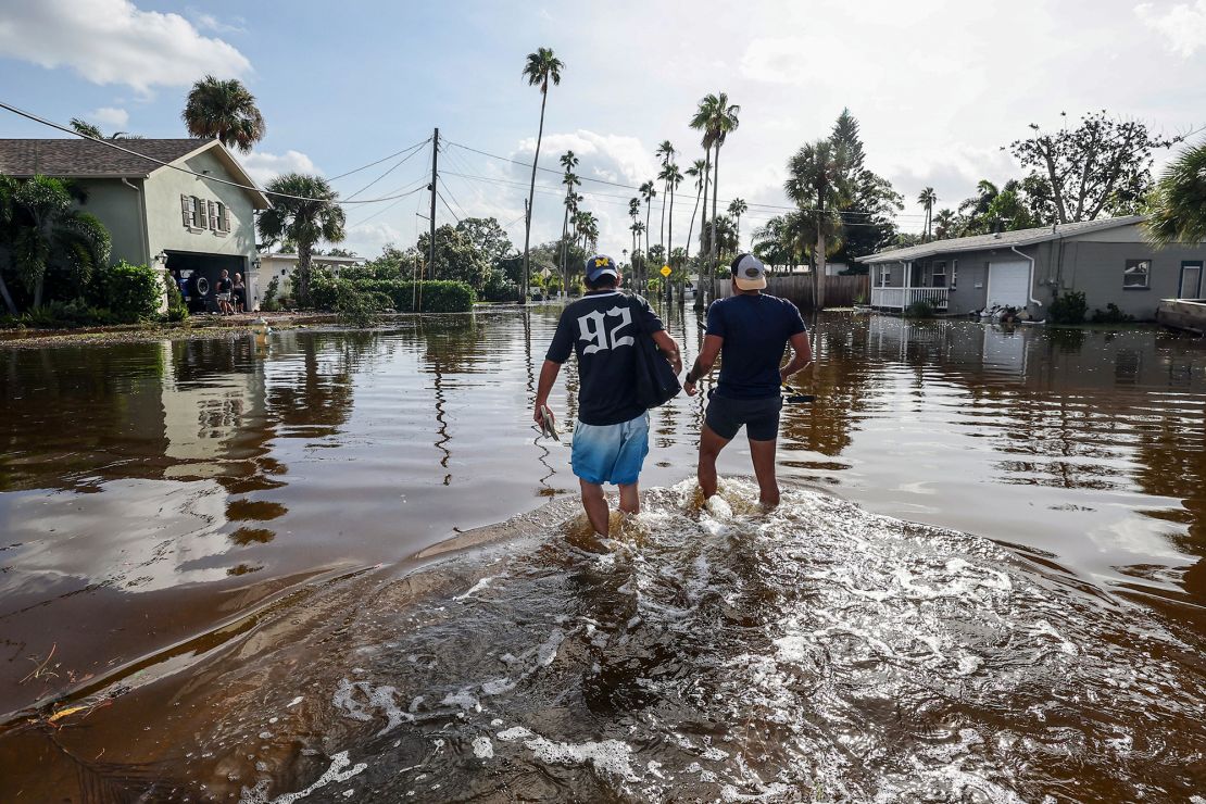 Thomas Chaves (left) and Vinny Almeida walk through the floodwaters of Hurricane Helene to reach Chaves' mother's home in the Shore Acres neighborhood on Friday, September 27, 2024, in St. Petersburg, Florida.